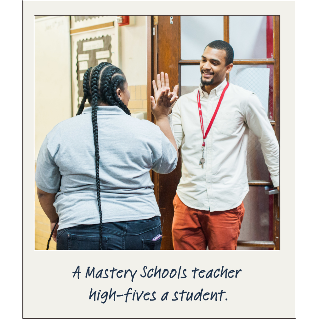 A young teacher high-fives a student in the hallway at Mastery Schools.